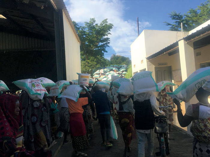 食料配布のトウモロコシの袋を抱えて家路を急ぐ人たち